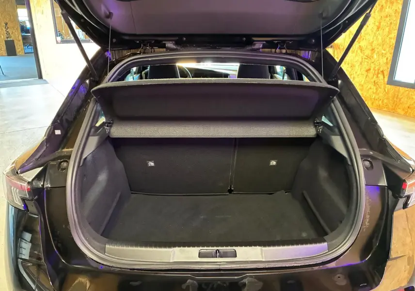 Coffre ouvert vu de l'arrière d'un Opel Mokka noir 2025, montrant l'espace de chargement vide et la tablette cache-bagages.