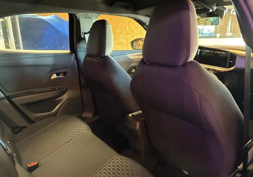 Vue intérieure arrière droite de l’Opel Mokka 2025 noir, sièges tissu noir avec coutures claires et tableau de bord moderne.