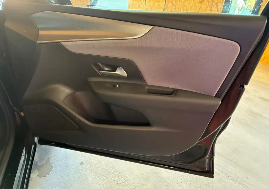 Vue intérieure de la porte côté gauche de l’Opel Mokka noir 2025, avec garniture tissu et plastique noir.