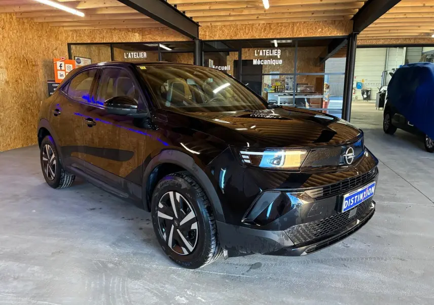 Opel Mokka 1.2 Turbo 145 Edition noir en 3/4 avant droit, avec jantes stylisées et calandre moderne dans un atelier.