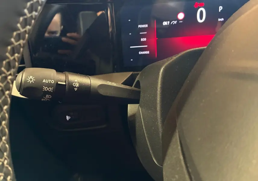 Détail intérieur du combiné d'instruments et du commodo d'éclairage à gauche du volant d'un Opel Mokka noir 2025.