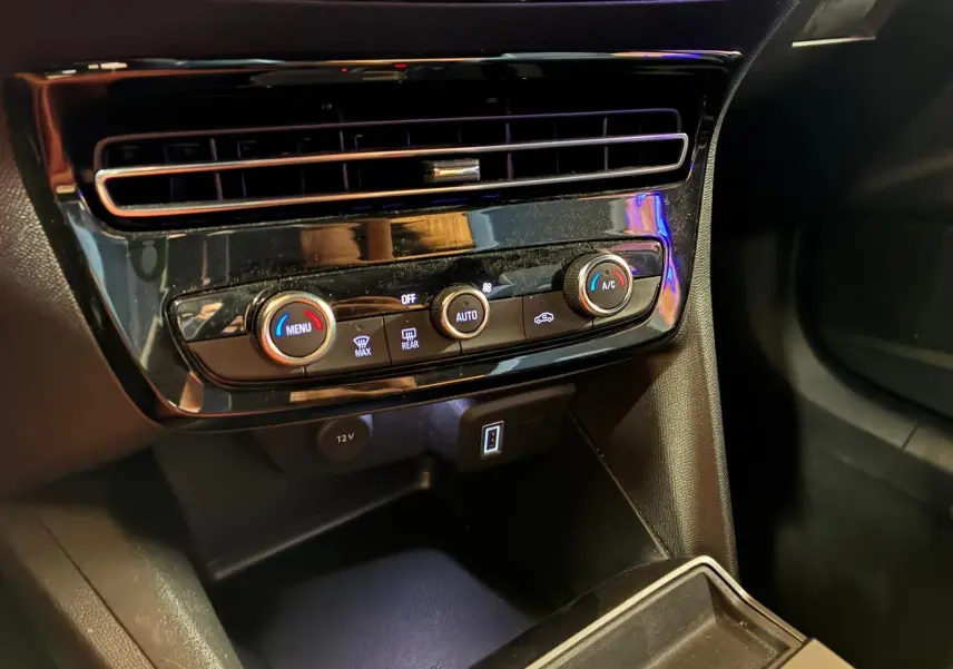 Vue rapprochée de la console centrale noire de l’Opel Mokka 1.2 Turbo 145 Edition avec commandes de climatisation et prises USB.