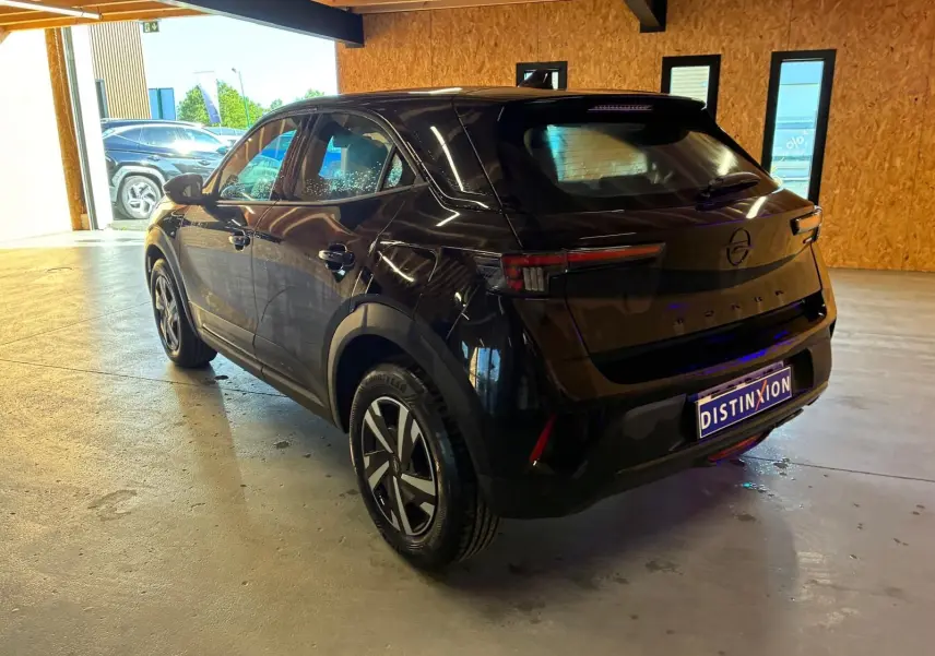 Opel Mokka noir 2025 vue 3/4 arrière droit en intérieur, avec jantes alliage et feux LED distinctifs.