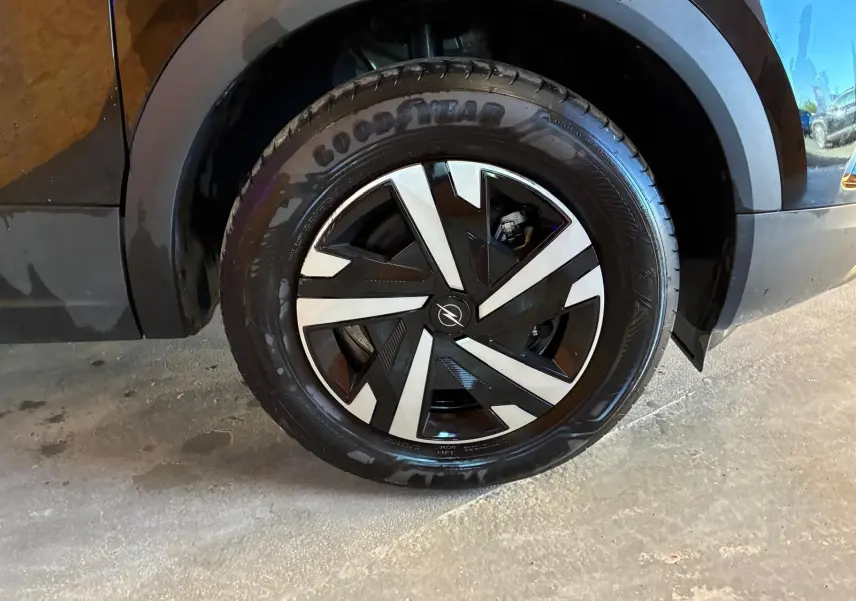 Gros plan sur la roue avant droite noire d’un Opel Mokka 2025 avec jante alliage au design géométrique bicolore.