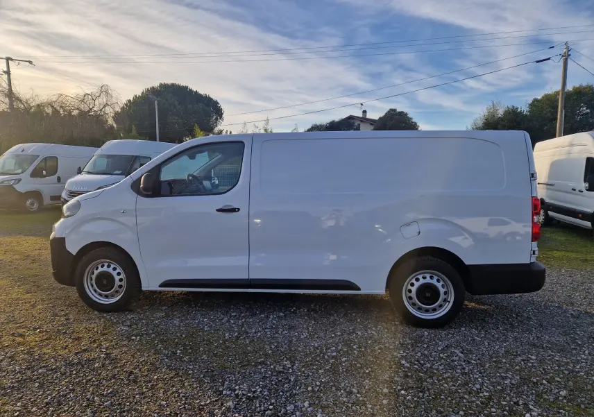 Vue de profil côté gauche d’un FIAT Scudo Fourgon blanc 2024, avec porte latérale coulissante et jantes acier simples.