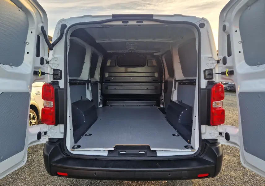 Vue arrière du fourgon FIAT Scudo XL blanc 2024, portes ouvertes montrant l’espace de chargement vide et protégé.