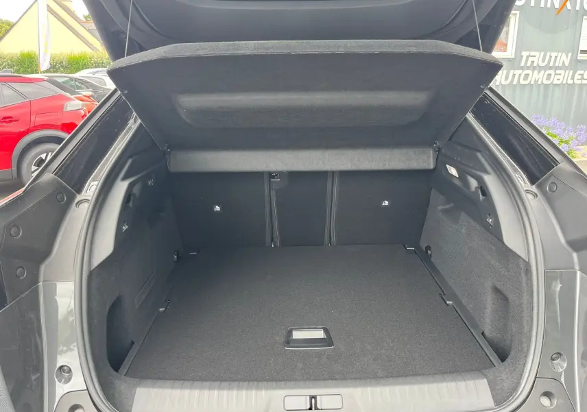 Coffre ouvert vu de l'arrière d'un Peugeot 3008 gris titane, intérieur spacieux et habillage noir.
