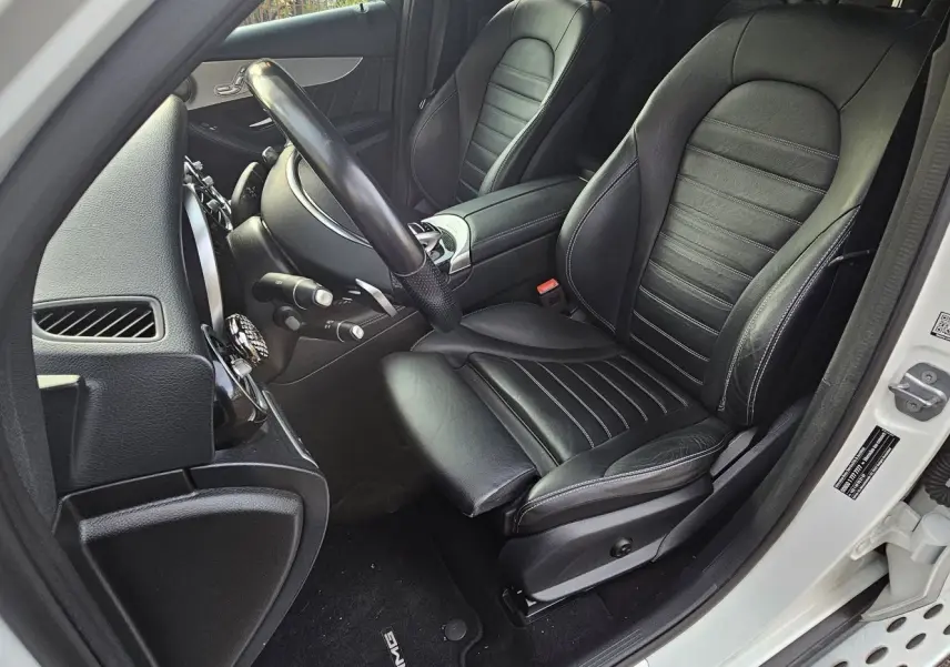 Intérieur côté conducteur du Mercedes GLC 220 Coupé blanc 2018, sièges cuir noir et tableau de bord visible.