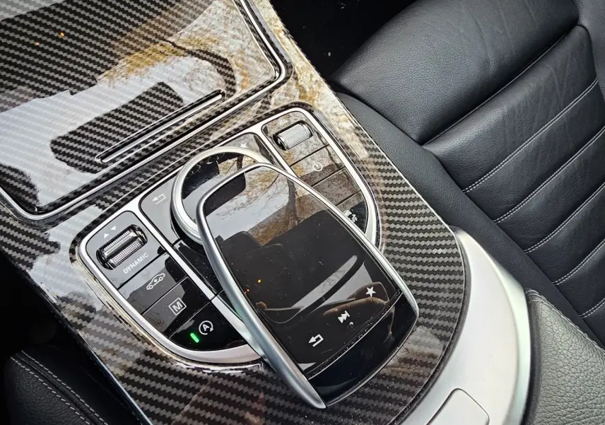 Gros plan sur la console centrale en carbone et le cuir noir des sièges du Mercedes GLC Coupé blanc 2018.