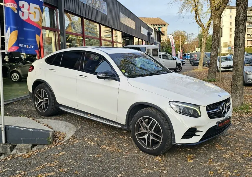 Vue 3/4 avant droite d'un Mercedes GLC 220 Coupé blanc 2018 avec jantes alliage et vitres teintées.