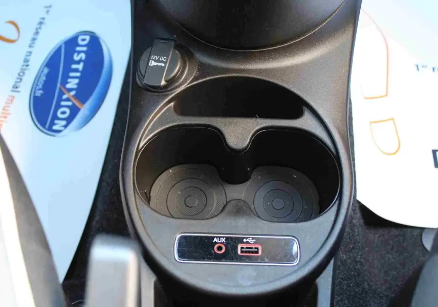 Vue 3/4 arrière droite d'une Fiat 500C Pastel Coral Red avec toit souple noir, en extérieur sur parking.