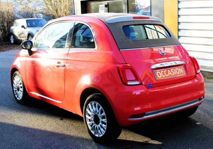 Vue 3/4 avant droite d'une FIAT 500C 2018 rouge Pastel Coral avec plaque "OCCASION" visible sur un parking.
