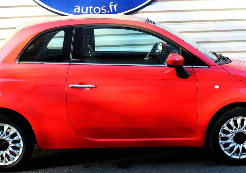 Vue de profil côté gauche d'une Fiat 500C 2018 rouge Pastel Coral avec jantes alliage et toit rigide fermé.