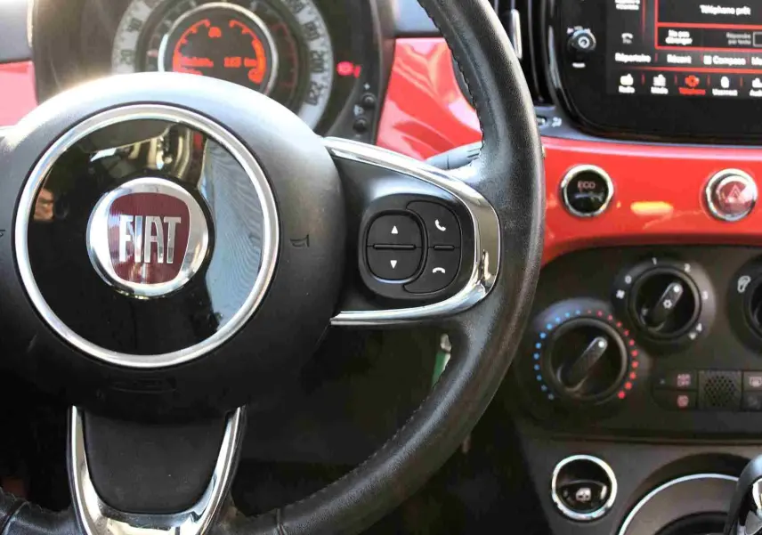 Gros plan sur la console centrale de la Fiat 500C 2018, montrant porte-gobelets, prise 12V, entrée AUX et port USB.