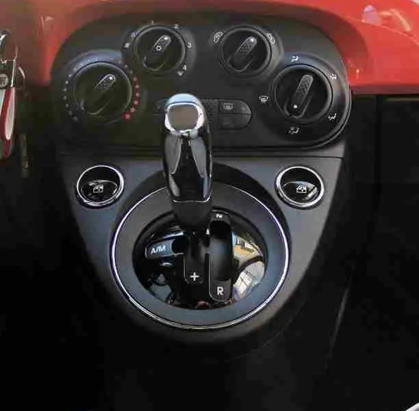 Vue rapprochée du volant et tableau de bord rouge pastel d'une Fiat 500C 2018 avec commandes intégrées au volant.