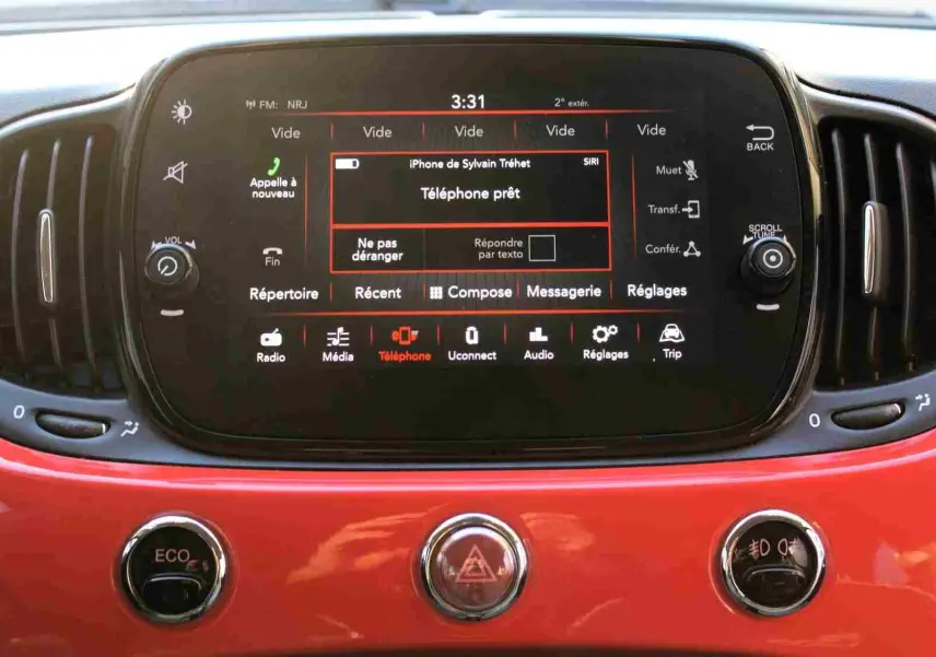 Vue rapprochée du tableau de bord rouge pastel d'une Fiat 500C 2018, avec écran tactile central allumé.