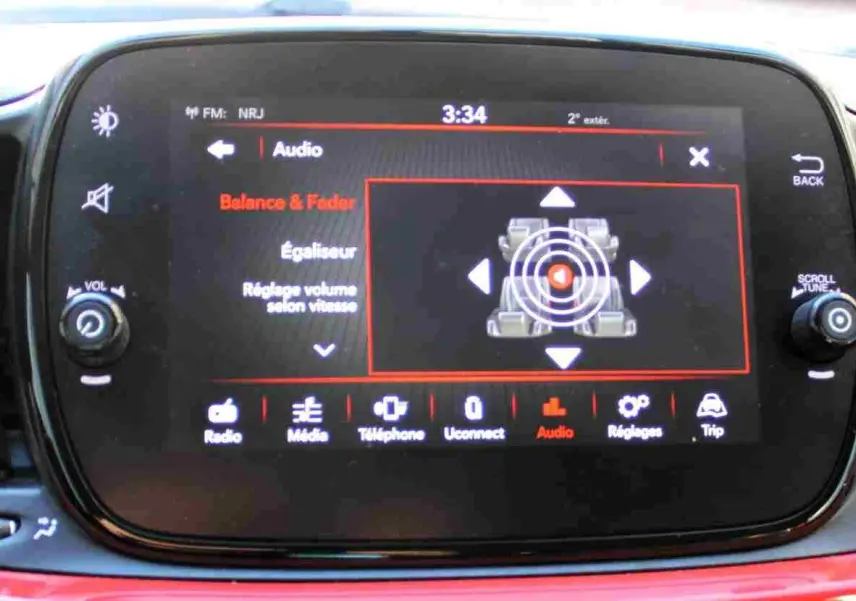 Écran tactile central de la Fiat 500C 2018 en Pastel Coral Red, affichant les réglages audio avec commandes autour.