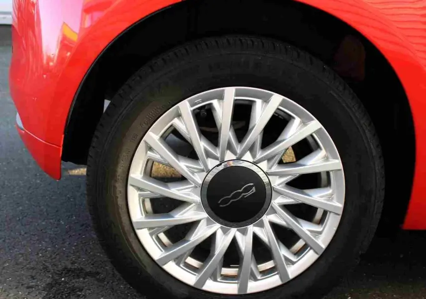 Gros plan sur l'emblème 500C rouge et chrome sur la porte côté droit d'une FIAT 500C Pastel Coral Red.