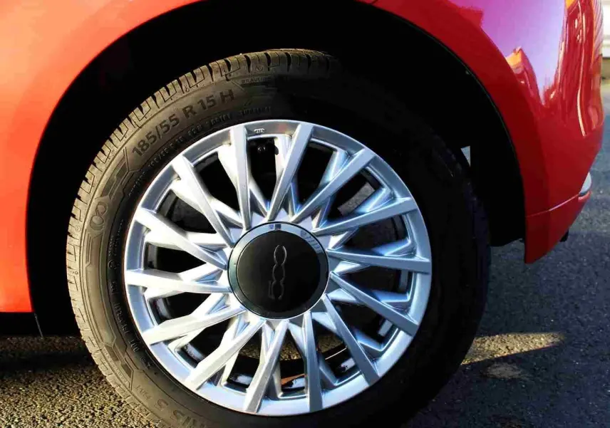 Vue 3/4 avant droite d'une Fiat 500C 2018 rouge pastel avec jantes alliage et toit ouvrant visible.