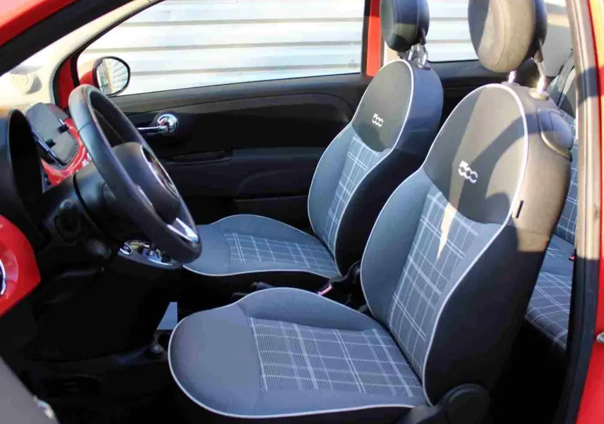 Vue intérieure côté conducteur de la FIAT 500C rouge Pastel Coral avec sièges gris à motifs et logo 500 brodé.