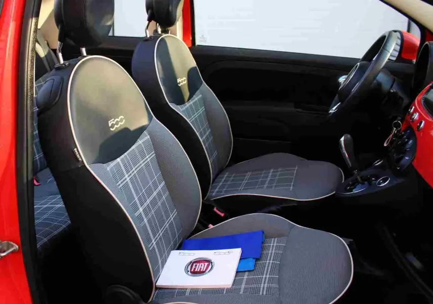 Vue intérieure côté gauche de la FIAT 500C rouge Pastel Coral avec sièges à motif écossais et logo 500 brodé.