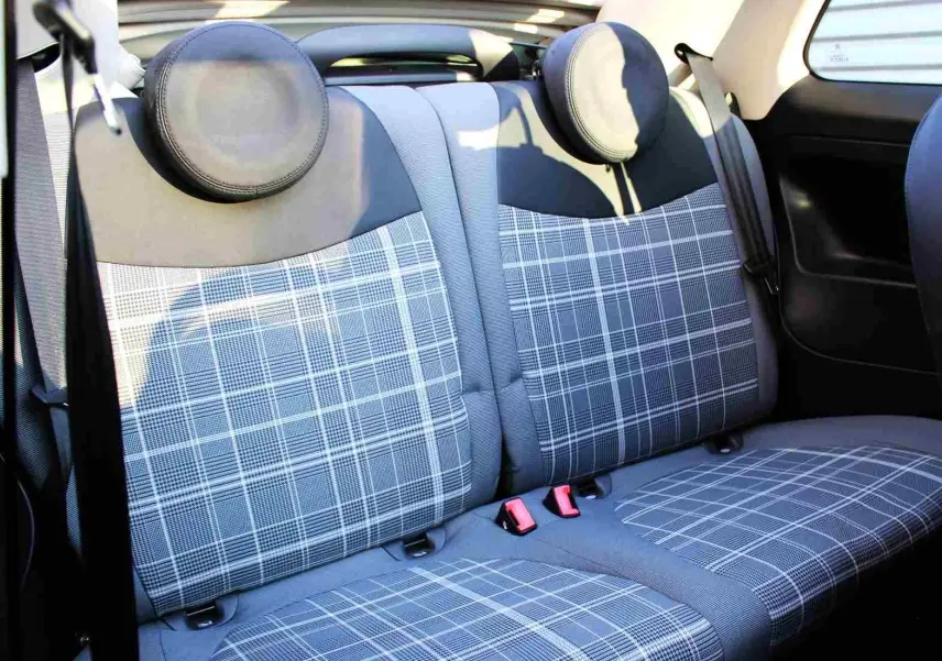 Fiat 500C Pastel Coral Red vue 3/4 avant droit, toit noir, devant un mur métallique avec logo Distinxion.