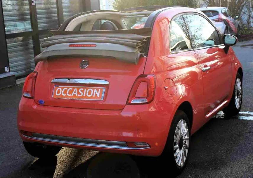 Profil côté gauche d'une FIAT 500C 2018 rouge Pastel Coral avec jantes alliage et toit rigide fermé.