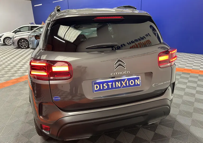 Vue arrière d’un Citroën C5 Aircross gris Platinium avec feux allumés dans un showroom intérieur.