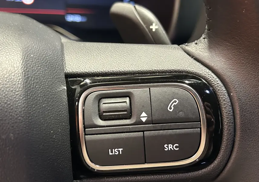 Gros plan sur les commandes multifonctions du volant en cuir noir du Citroën C5 Aircross 2023, finition Shine.