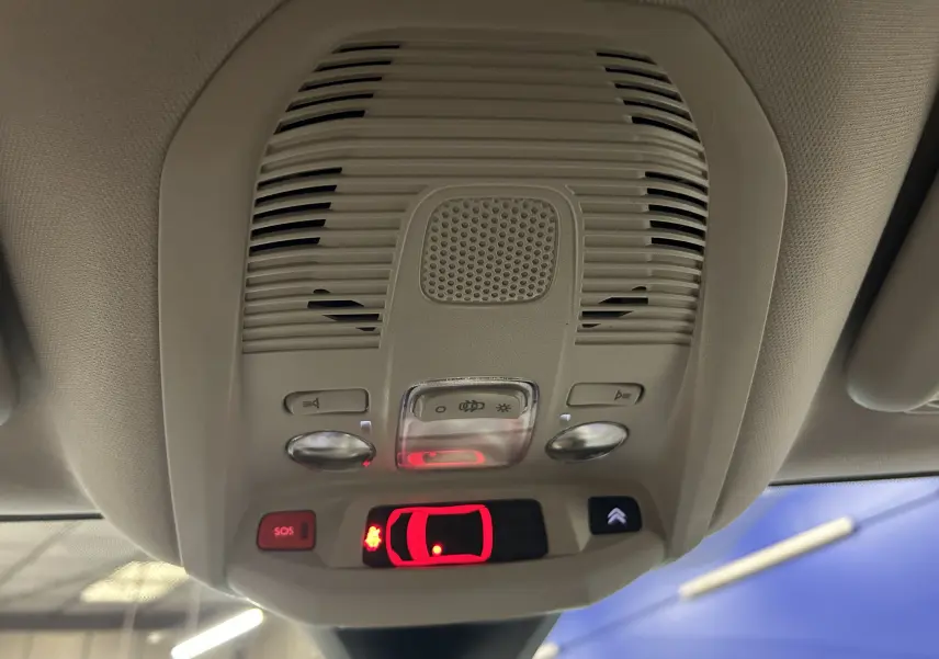 Vue intérieure en contre-plongée du plafonnier gris clair avec commandes lumineuses et bouton SOS du Citroën C5 Aircross 2023.