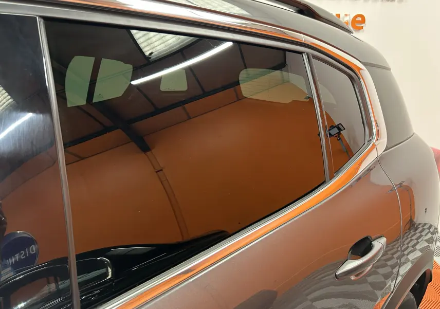 Vue rapprochée du côté arrière droit d’un Citroën C5 Aircross gris Platinium avec vitres teintées et poignée de porte visible.