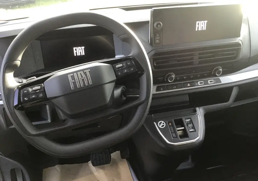 Vue intérieure centrée sur le volant et le tableau de bord numérique du Fiat Scudo Fourgon blanc, avec écran tactile et commandes intégrées.