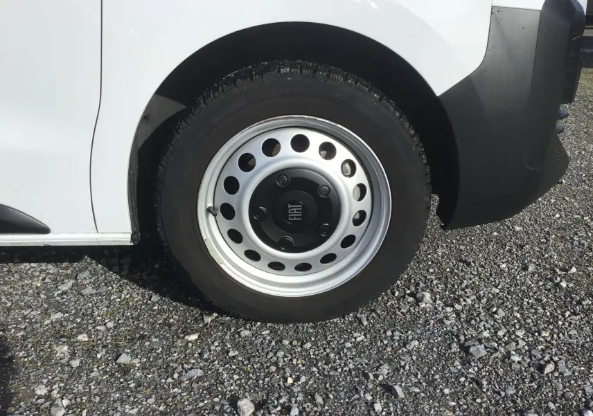 Gros plan sur la roue avant droite d’un FIAT Scudo Fourgon blanc avec jante acier et logo central FIAT.