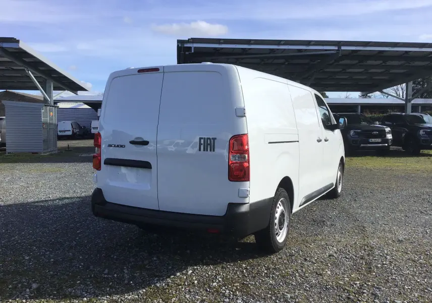 Vue 3/4 arrière droite d’un fourgon FIAT Scudo blanc 2024 avec porte arrière double et pare-chocs noir.