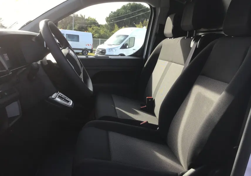Intérieur du FIAT Scudo Fourgon blanc 2024, vue côté conducteur sur les sièges avant en tissu noir et tableau de bord.
