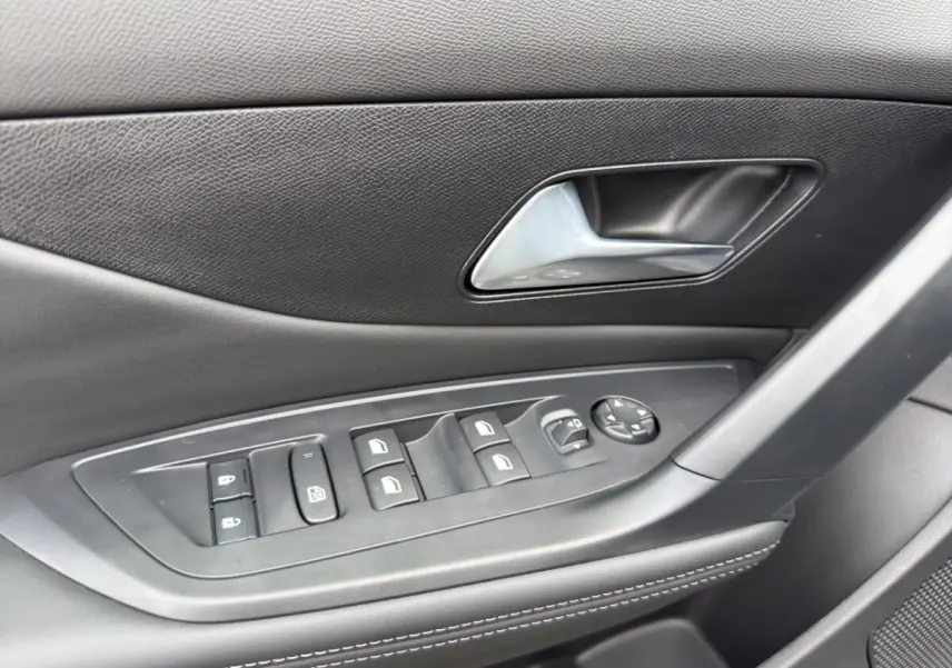 Gros plan sur la commande des vitres et rétroviseurs côté conducteur de la Peugeot 308 Hybrid gris foncé, intérieur noir.