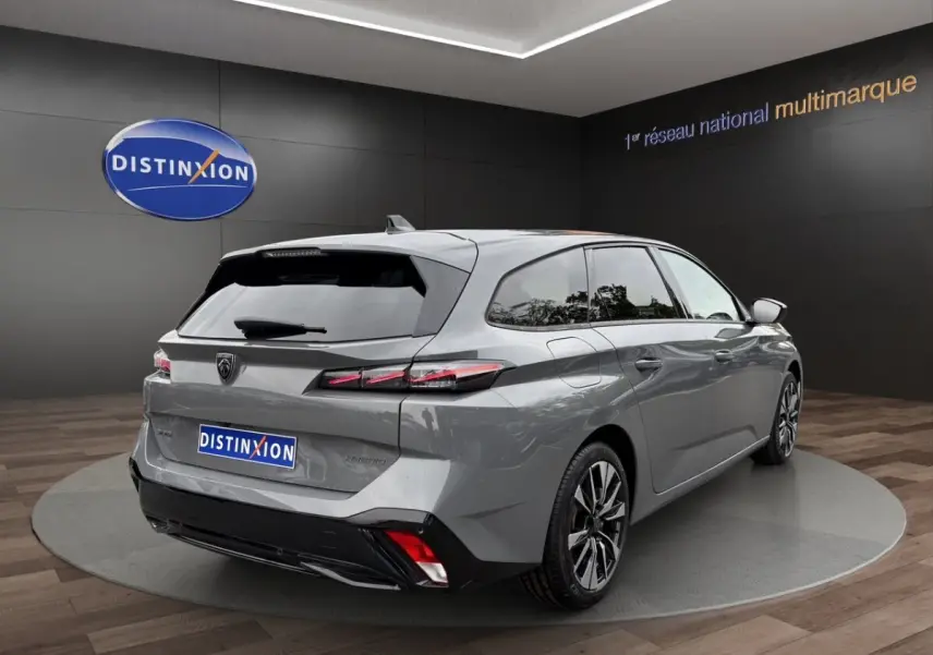 Vue 3/4 arrière droite d'une Peugeot 308 Hybrid gris foncé avec feux arrière LED et jantes alliage distinctives.