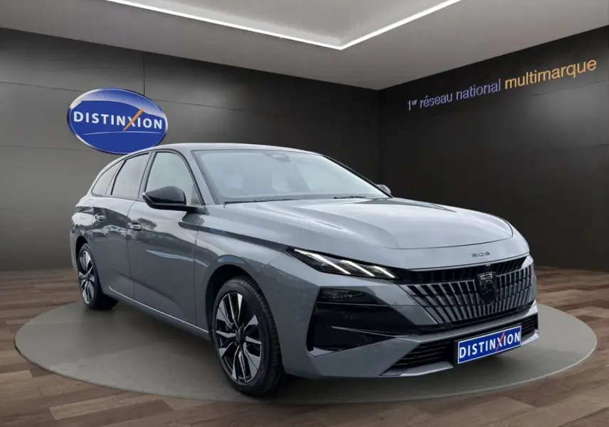 Peugeot 308 Hybrid gris foncé vue 3/4 avant droit, avec calandre noire et phares LED fins en showroom.