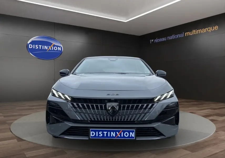 Vue frontale d'une Peugeot 308 Hybrid gris foncé avec calandre distinctive et phares LED fins allumés.