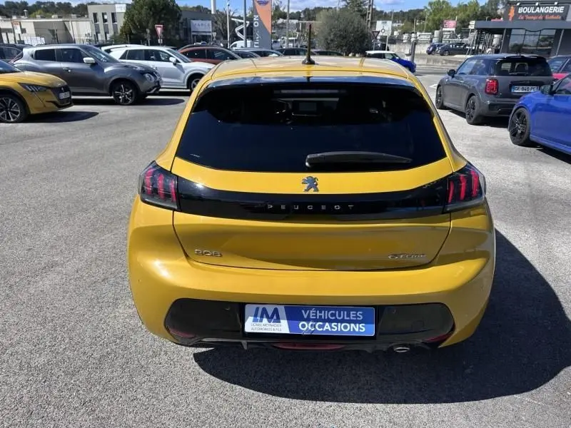 Vue arrière d'une Peugeot 208 GT line jaune faro de 2020, avec feux arrière à griffes et logo Peugeot central.