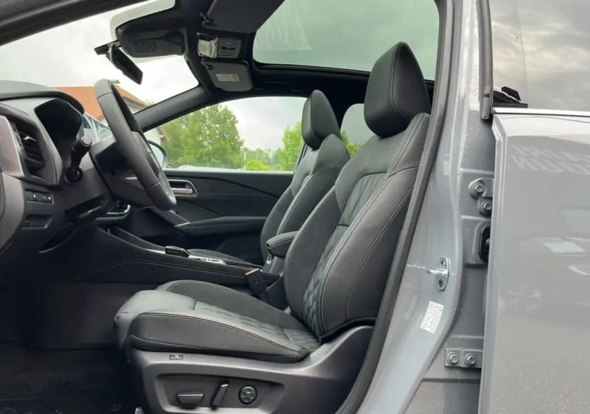 Vue intérieure côté conducteur du Nissan Qashqai E-POWER 205 Tekna Plus gris argile avec sièges cuir et toit panoramique ouvert.