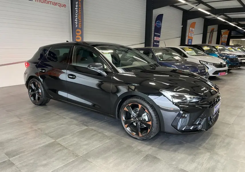 Vue 3/4 avant droite d'une CUPRA Leon noire avec jantes alliage 18'' cuivrées dans un showroom.