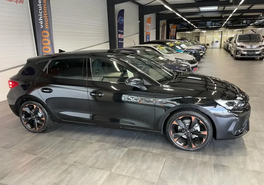 Vue de profil côté gauche d'une CUPRA Leon noire avec jantes alliage 18'' cuivrées en concession.