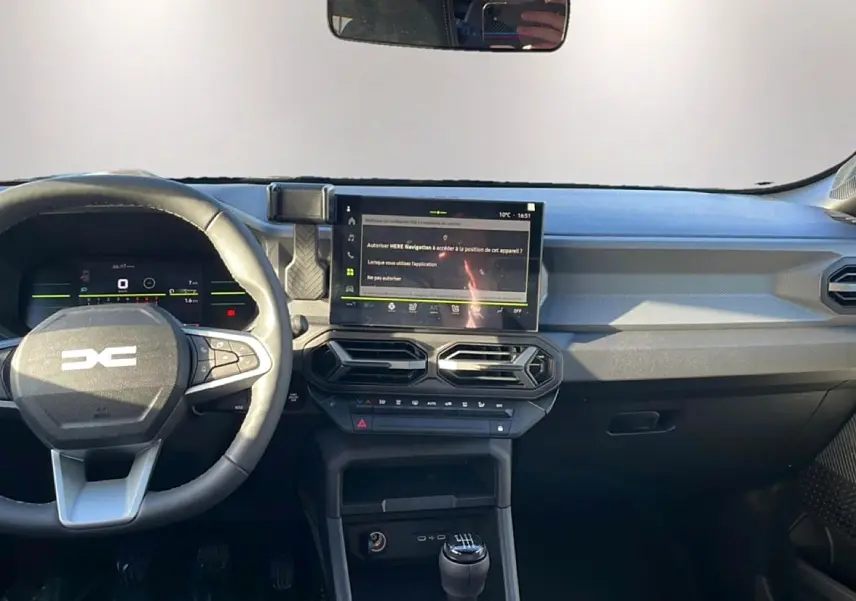 Vue intérieure du tableau de bord du Dacia Duster 2026 noir, avec volant multifonction, écran tactile et levier de vitesse manuel.
