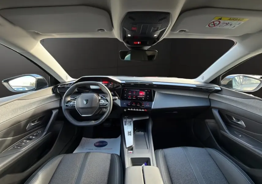 Vue intérieure avant centrée du tableau de bord et volant cuir de la Peugeot 308 Hybrid 145 e-DCS6 Allure 2025.