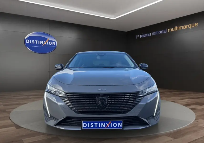 Vue avant frontale de la Peugeot 308 Hybrid gris foncé avec calandre noire et feux LED verticaux allumés.