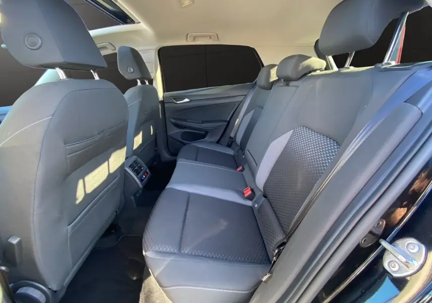 Vue intérieure arrière côté droit de la Volkswagen Golf VIII noire, montrant les sièges arrière en tissu noir et gris.