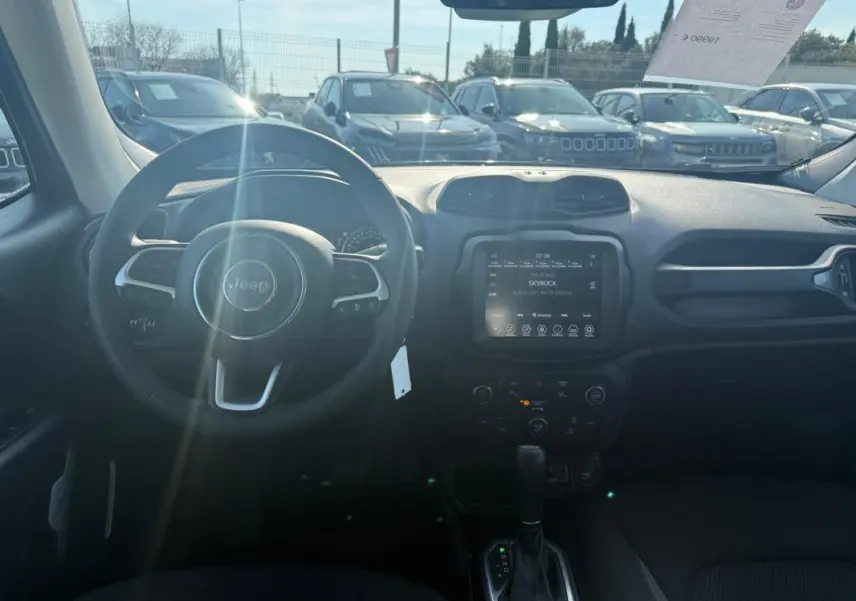 Vue intérieure du tableau de bord du Jeep Renegade 2023 avec écran tactile et volant multifonction, lumière naturelle entrant par le pare-brise.