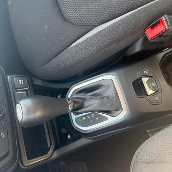 Gros plan sur la console centrale du Jeep Renegade bleu 2023, montrant le levier de vitesse automatique et le siège conducteur noir.