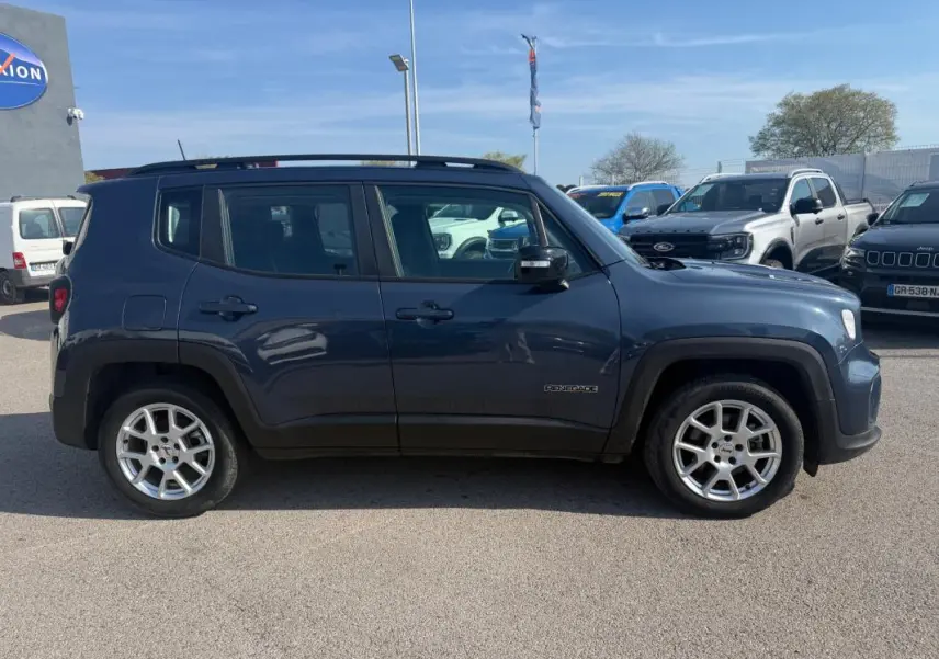 Vue latérale gauche d'un Jeep Renegade bleu 2023 avec jantes alliage et barres de toit visibles.